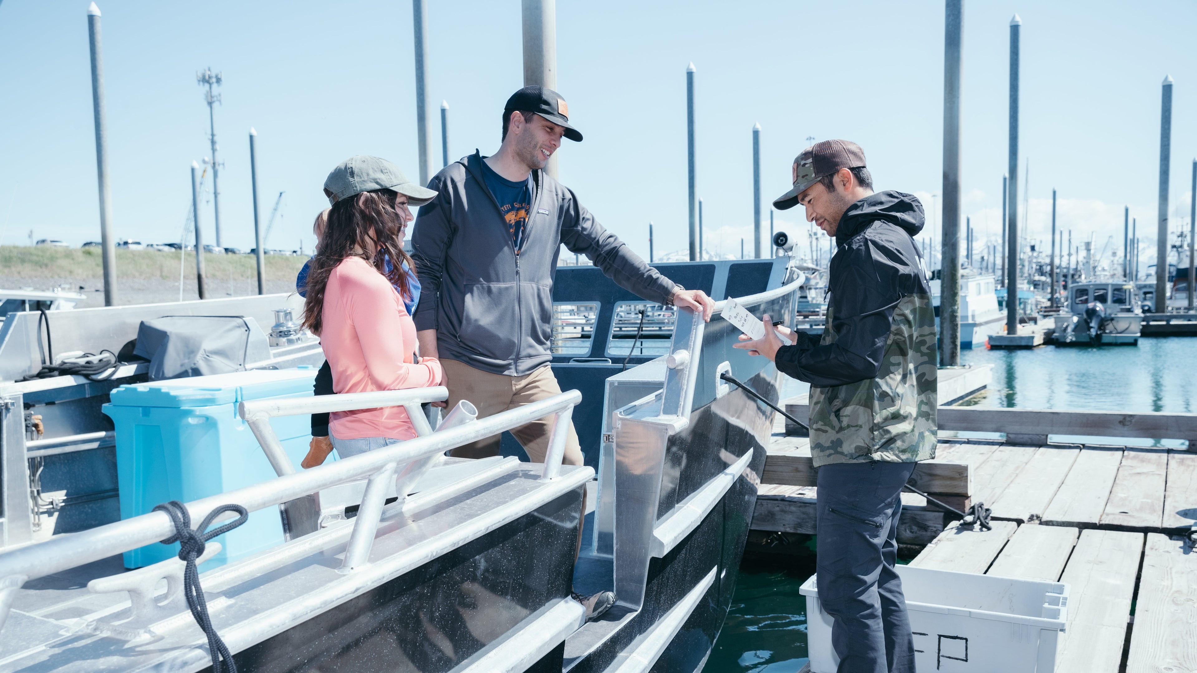 Husband and wife stand on a black boat in the Homer Boat Harbor offloading fish with Homer Fish Processing in Homer, Alaska.